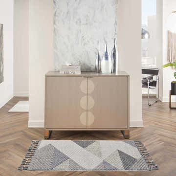 Living room scene with a grey slate Nourison Paxton rug, wood floors, and modern cabinet.