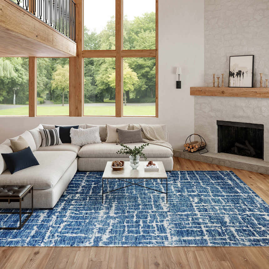 Bright living room with a Nourison Luna Blue Silver rug, sectional sofa, fireplace, and large windows.