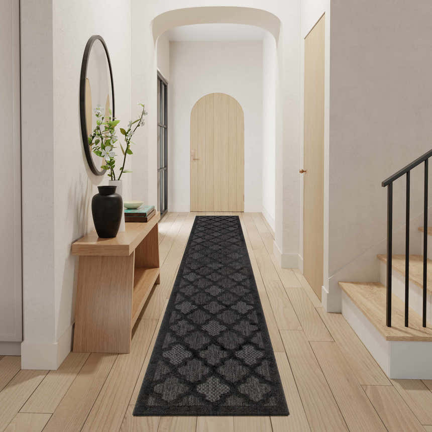 Entryway with Nourison Easy Care Charcoal Black Modern Area Rug runner, wood floors, console table, and arched doorways.