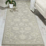 Living room scene with a light taupe Nourison Zephyr runner rug, ivory sofa, and potted plant on wood floors.