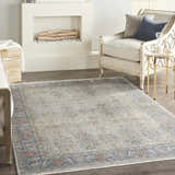 Living room with a fireplace and Nourison Starry Nights Grey Vintage Area Rug, cream armchair, and gold accent table.