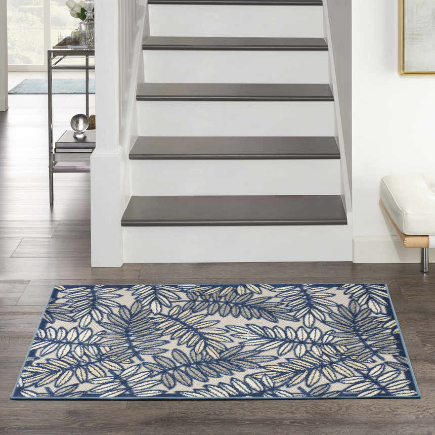 Entryway with Nourison Aloha Ivory Navy Tropical Area Rug, dark wood floors, white stairs, and modern decor.