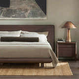 Bedroom scene with a Four Hands Grid Jute Rug, natural fiber rug under a wood bed, and a copper lamp on a nightstand. Roomscene-Rectangle