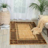 Light-filled room with a beige Nourison Vallencierre vintage rug, wood floors, sheer curtains, and neutral accents.
