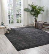 Bright room featuring a Nourison OCEAN Onyx rug, bench, and potted plant. The rug is black with a subtle, modern design.