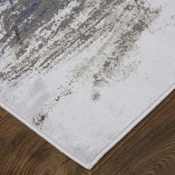 Close-up of Feizy Gaspar rug. Modern abstract design in blue, gray, and white on a distressed, textured surface. Corner