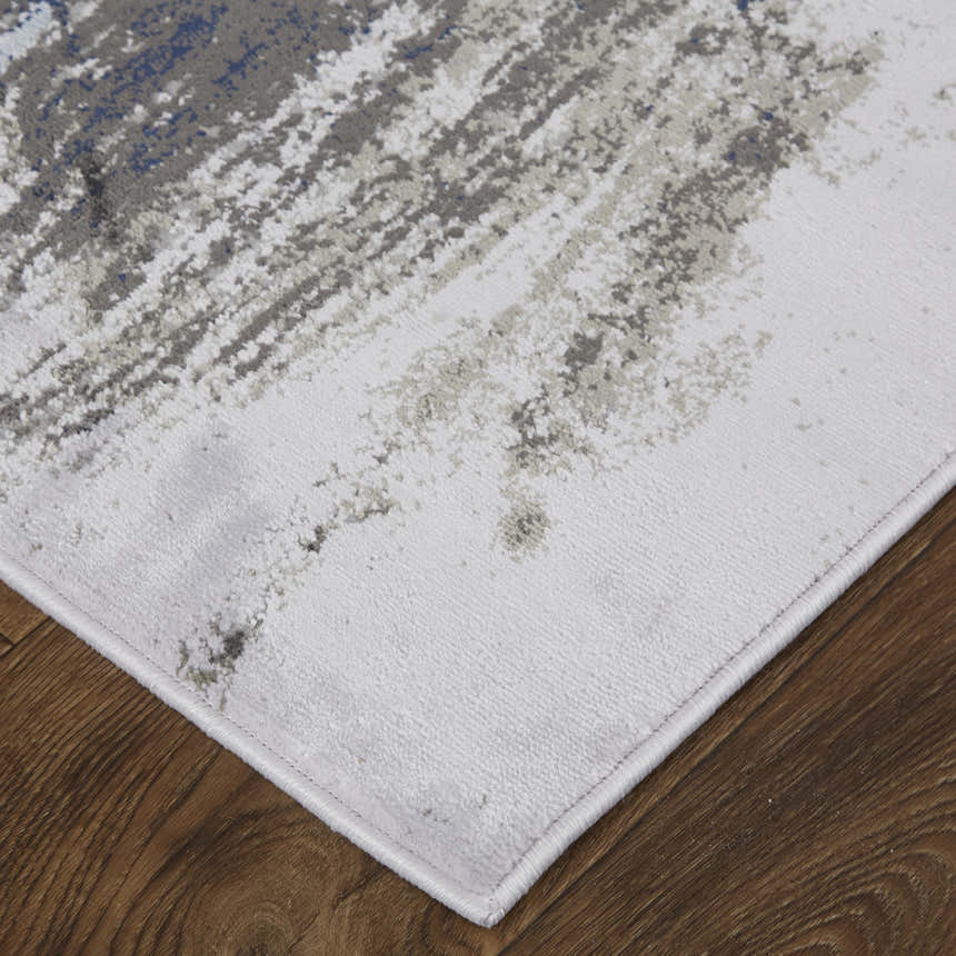 Close-up of Feizy Gaspar rug. Modern abstract design in blue, gray, and white on a distressed, textured surface. Corner