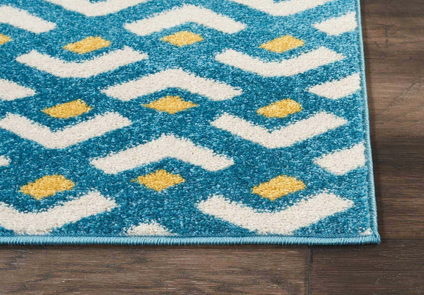 Close-up of the Nourison Harper Blue rug. Features a colorful geometric pattern with light blue, white, and yellow hues.