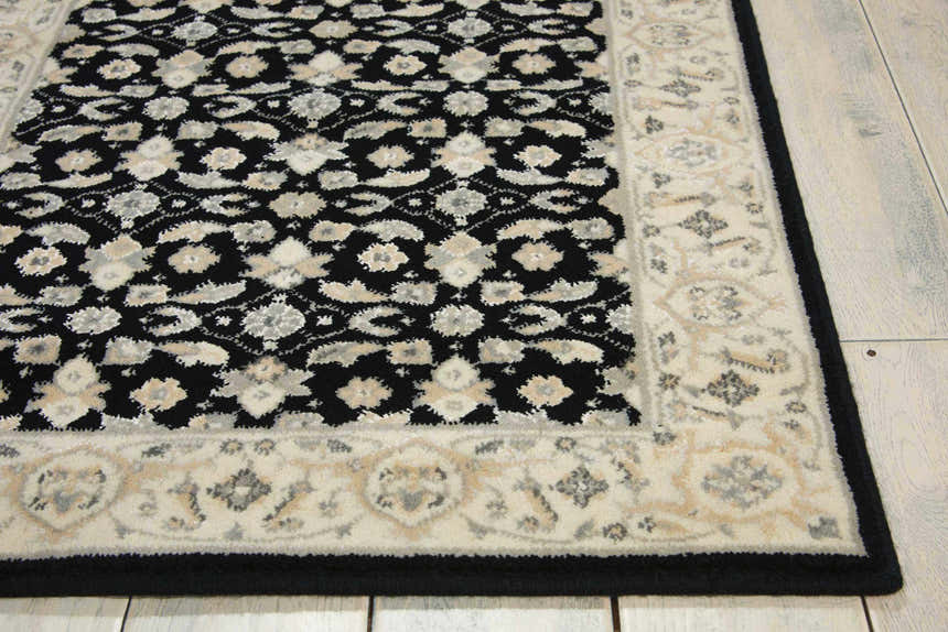 Close up of the Nourison Persian Empire Black Persian rug's floral pattern and border on wood floors.