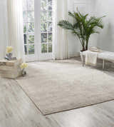 Light-filled room with a Nourison OCEAN Mist rug, white bench, and potted palm. Modern, serene space.