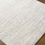 Close-up of the Sezja Beige Luxe Area Rug. Features a textured, contemporary design in beige, cream, and black. Corner
