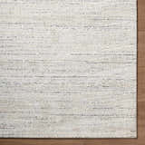 Close-up of the Sezja Beige Luxe Area Rug featuring a subtle horizontal line pattern in beige, cream, and black. Corner