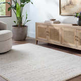 Living room with a beige Sezja Luxe Area Rug, light wood cabinet, tan chair, and potted plant. Roomscene-Rectangle
