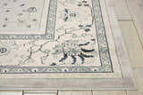 Close-up of the Nourison Maymana Silver Persian rug, showing floral patterns and gray border on light wood flooring.