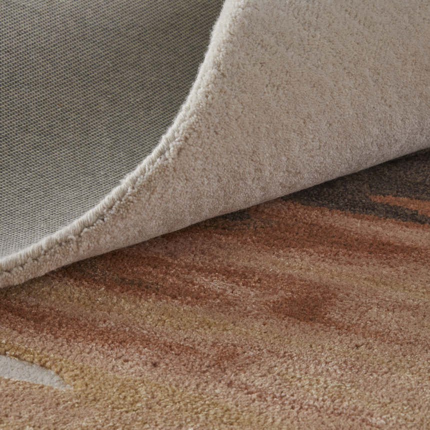 Close-up of the Feizy Anya rug showing the abstract pattern, red, brown, and orange tones, and hand-tufted texture. Fold