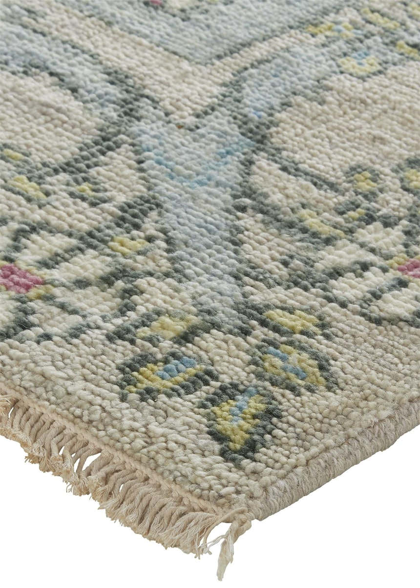 Close-up of the hand-knotted Feizy Beall rug. Ivory wool rug with a traditional floral pattern in pink, green, and blue. Corner