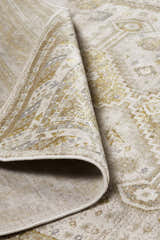 Close-up of Feizy Aura Modern Persian rug in gold and ivory, showing the traditional pattern and jute backing. Fold