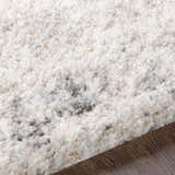 Close-up of the plush Hilotongan Area Rug. Cream shag rug with light and medium gray abstract pattern. Soft texture. Texture