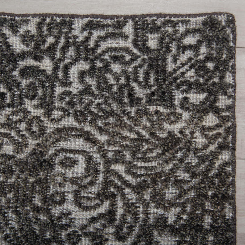 Close up of the hand knotted Rizzy HTN720 area rug. Gray and ivory wool with a traditional farmhouse pattern and textured pile. Corner