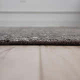 Close-up of the textured, hand-knotted Rizzy HTN720 area rug in gray and ivory on a light wood floor. Pile