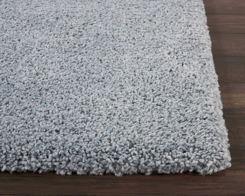 Close-up of the plush texture of the Nourison Malibu Shag Slate rug on dark wood flooring.