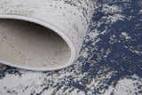 Close up of Feizy Gaspar rug showing blue, gray, and white distressed splatter pattern and jute backing. Fold
