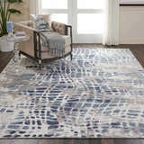 Living room scene with Nourison Urban Decor Ivory/Grey rug, beige chair, and hardwood floors. Modern, stylish design.