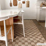 Farmhouse kitchen with Ionut Checkered Jute Area Rug. Beige and tan rug under a white table and chairs. Wood cutting boards on wall. Roomscene-Rectangle