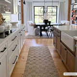 Farmhouse kitchen with a tan Ionut Checkered Jute Area Rug runner on wood floors, white cabinets, and dining area. Roomscene-Runner