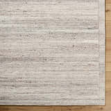 Close up of the Blenda Beige Area Rug. Hand tufted wool rug with beige, charcoal, and gray striations. Corner