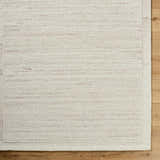Close-up of the Blenda Tan Area Rug showing its beige wool texture and subtle horizontal pattern on wood flooring. Corner