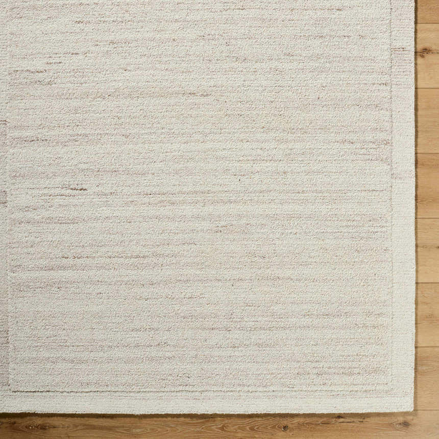 Close-up of the Blenda Tan Area Rug showing its beige wool texture and subtle horizontal pattern on wood flooring. Corner