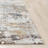 Close-up of the Rizzy JAS732 area rug. Abstract design in beige, black, blue, dark red, and ivory. Machine woven texture. Corner