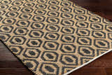Close-up of the Isaye Charcoal Area Rug showing its jute texture and geometric dark beige and black pattern. Corner