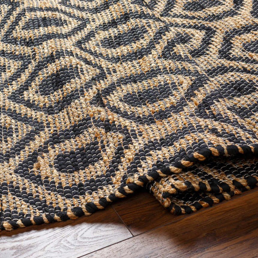 Close-up of the hand woven Isaye Charcoal Area Rug, featuring a dark beige and gray contemporary pattern. Fold