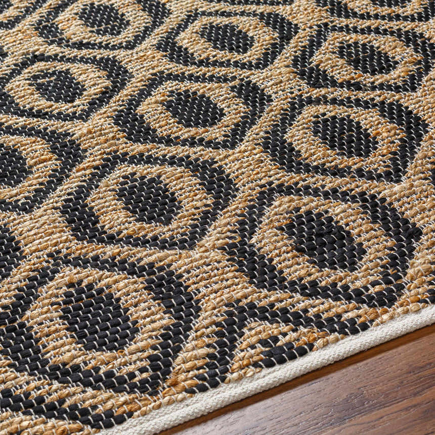 Close-up of the hand-woven Isaye Charcoal Area Rug, featuring a geometric pattern in jute and black recycled fabric. Texture