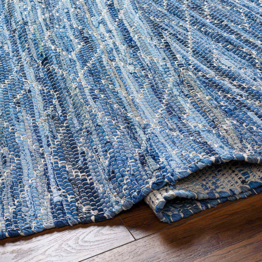Close-up of the hand woven Gurit Blue Area Rug. Recycled fabric in shades of blue, gray, and white. Contemporary style. Fold