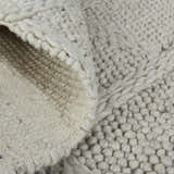 Close-up of the Feizy Berkeley rug. Ivory and gray wool with a hand-woven, interlocking checkered texture. Fold