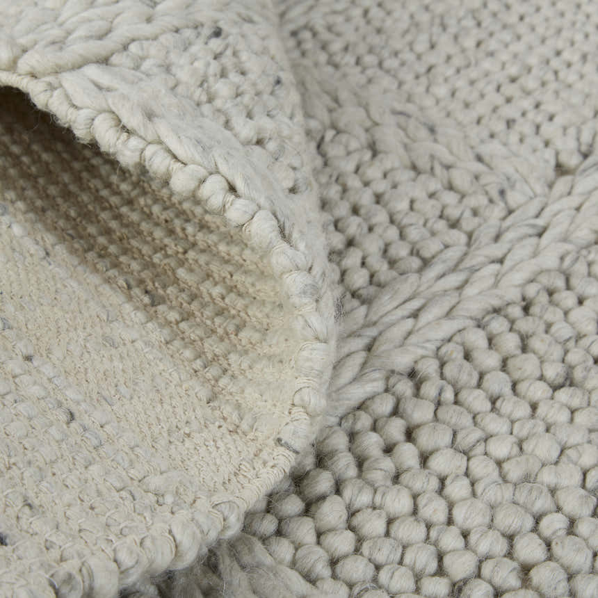 Close-up of the Feizy Berkeley rug. Ivory and gray wool with a hand-woven, interlocking checkered texture. Fold