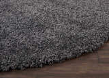 Close-up of the plush texture of the Nourison Malibu Shag Dark Grey rug on a dark wood floor.