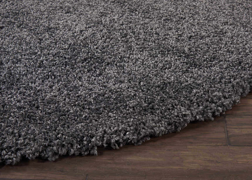 Close-up of the plush texture of the Nourison Malibu Shag Dark Grey rug on a dark wood floor.