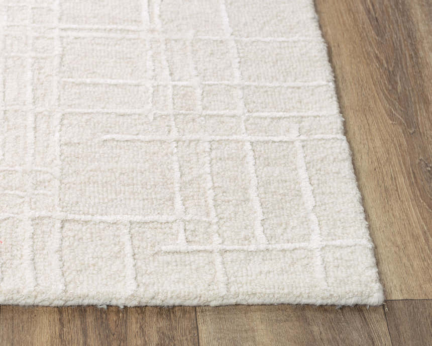 Close-up of the ivory Rizzy JZZ973 area rug. Hand-tufted wool rug with a subtle geometric pattern and soft texture. Corner
