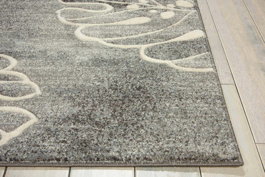 Close-up of the Nourison Maxell Grey rug. Modern design with a gray base and raised white floral pattern. Soft texture.