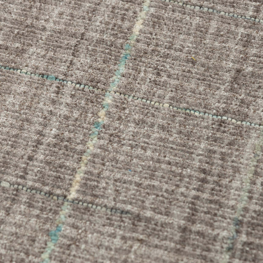 Close up of the Rizzy KIK691 area rug showing its gray wool texture and subtle blue grid pattern. Texture
