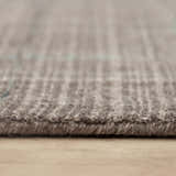 Close-up of the hand-loomed Rizzy KIK691 area rug showing wool and tencel fibers and subtle blue, red, and ivory pattern. Pile