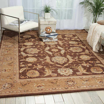 Living room scene with a Nourison 3000 Brown Persian rug, white chair, and light wood floors. Elegant and inviting.