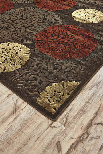 Close-up of the Feizy Saphir rug showing the taupe, red, and tan polka dot floral pattern and soft, textured pile. Corner