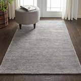 Living room scene with Nourison Weston Silver Birch rug, gray ottoman, dark wood floors, and sheer white curtains.