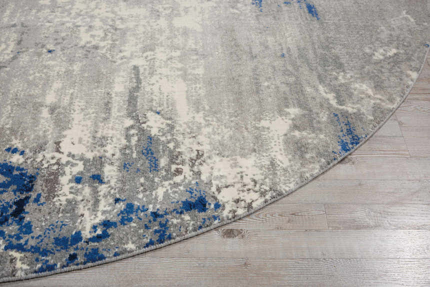 Close-up of the round Nourison Twilight Blue Grey rug showing its abstract pattern and blue accents on wood floor.
