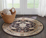 Entryway with a round Nourison Walden Bistre rug, dark wood floors, white door, and a basket of blankets.